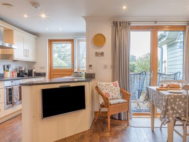 A kitchen and dining area with a countertop and a chair with cushions at 5 Court Cottage Hillfield Village Dartmouth