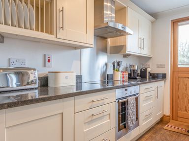 A kitchen with white cabinets a stainless steel oven a toaster and a wooden door at 5 Court Cottage Hillfield Village Dartmouth