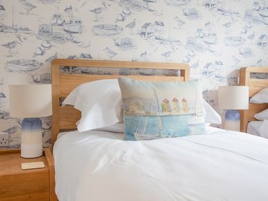A bedroom with wooden beds white bedding a decorative pillow and table lamps at 5 Court Cottage Hillfield Village Dartmouth