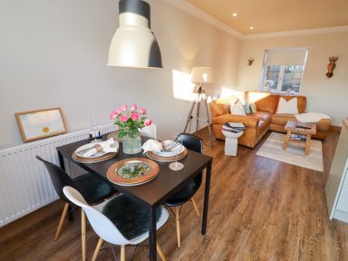 A dining room with a table set for two and a sofa at Nene's Nest in Alnwick