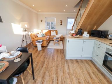 A living room with a sofa, dining table, and kitchen area at Nene's Nest in Alnwick
