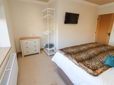 A bedroom with a bed, dresser, and clothes hanger at Nene's Nest in Alnwick