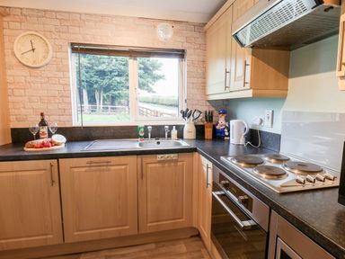 A kitchen with a stove sink kettle and utensils on countertops at Handale Banks Farm Lodge in Liverton