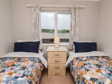 A bedroom with two single beds with floral bedcovers and a bedside table with a lamp between at Handale Banks Farm Lodge in Liverton
