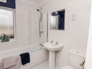 A bathroom with a bathtub shower combination a pedestal sink a toilet and a window at Handale Banks Farm Lodge in Liverton