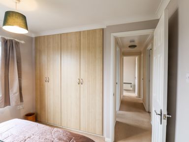 A bedroom with a bed a large wooden wardrobe and a hallway visible through an open door at Handale Banks Farm Lodge in Liverton