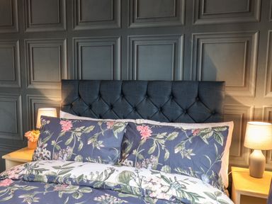 A bed with floral bedding and two bedside tables with lamps against a paneled wall at Handale Banks Farm Lodge in Liverton