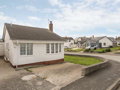 A white detached house with a driveway and a curved brick wall at 31 Sisial Y Mor in Rhosneigr