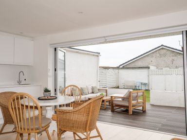 A dining area with chairs and a table next to an open patio with outdoor seating at 31 Sisial Y Mor in Rhosneigr