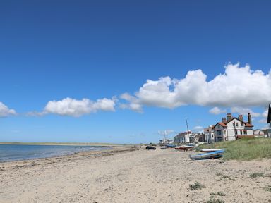 A sandy beach with boats and houses along the shore at 31 Sisial Y Mor in Rhosneigr