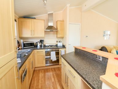 A kitchen with wooden cabinets a gas stove microwave kettle and toaster at Mojo Mullacott near Ilfracombe