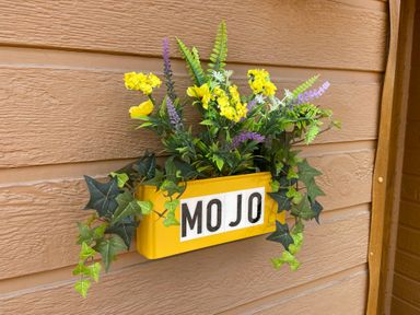 A planter with yellow purple and green plants on a wooden wall at Mojo in Mullacott near Ilfracombe