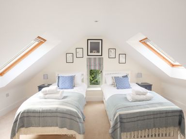 A bedroom with two single beds under slanted ceilings with skylights at Traeth Ora in Moelfre
