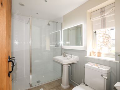 A bathroom with a walk-in shower sink toilet and window with blinds at Traeth Ora in Moelfre