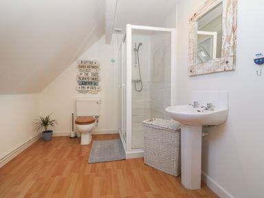 A bathroom with a toilet sink shower and wicker laundry basket at Wig Carna in Holyhead