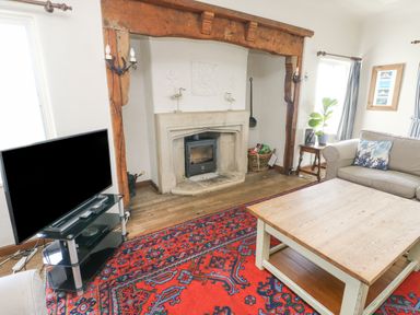 A living room with a fireplace a wooden coffee table a television on a stand and a sofa with cushions at Wig Carna in Holyhead