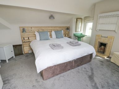 A bedroom with a bed towels on it a wooden headboard a green sink and a fireplace at Wig Carna in Holyhead