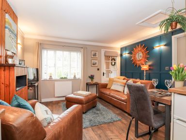 A living room with brown leather sofas a wooden floor and a dining table with chairs at Inny Brook Cottage in Davidstow near Camelford
