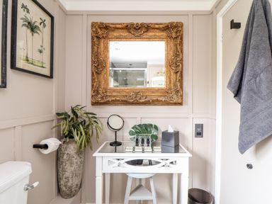 A bathroom with a white table holding toiletries under a gold framed mirror at Inny Brook Cottage Davidstow near Camelford