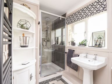 A bathroom with a shower cubicle white sink window with patterned blind and white corner cabinet at Inny Brook Cottage Davidstow near Camelford