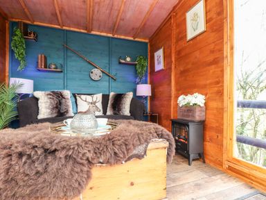 A small sitting room with a black sofa and a coffee table covered with a brown furry throw at Inny Brook Cottage Davidstow near Camelford