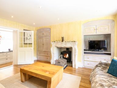 A living room with a wooden coffee table fireplace and a television at The Farmhouse in Felmingham near North Walsham