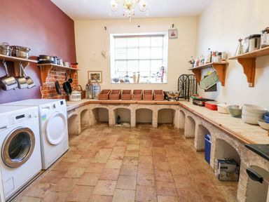 A utility room with washing machine dryer baskets bowls and shelves at The Farmhouse in Felmingham near North Walsham