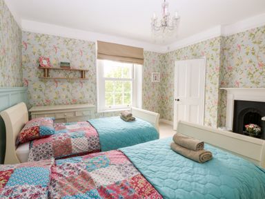 A bedroom with two single beds covered with blue and patchwork quilts at The Farmhouse in Felmingham near North Walsham