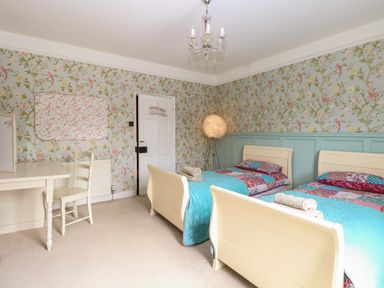 A bedroom with two single beds a desk chair and floral wallpaper at The Farmhouse in Felmingham near North Walsham