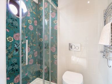 A bathroom with a shower featuring floral wallpaper and a white toilet at The Farmhouse in Felmingham near North Walsham