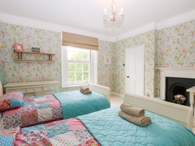 A bedroom with two single beds with blue quilts and patchwork blankets at The Farmhouse in Felmingham near North Walsham