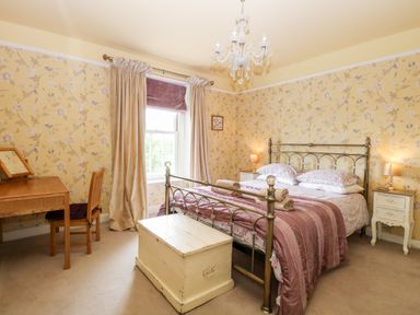 A bedroom with a metal bed frame wooden chest two bedside tables and a wooden desk at The Farmhouse in Felmingham near North Walsham