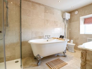 A bathroom with a clawfoot bathtub a shower enclosure a toilet and a wooden bath tray at The Farmhouse in Felmingham near North Walsham