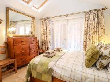 A bedroom with a wooden dresser chairs and a bed with green pillows and folded towels at The Farmhouse in Felmingham near North Walsham