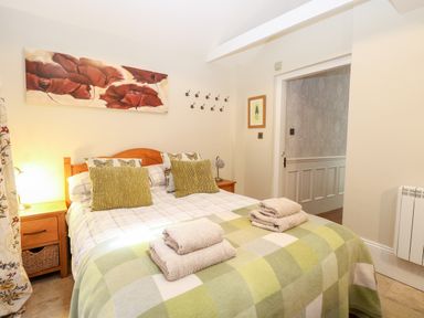 A bedroom with a double bed two bedside tables and folded towels at The Farmhouse in Felmingham near North Walsham
