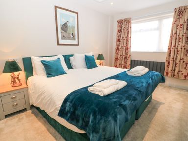 A bedroom with a double bed blue throw pillows blue blanket and lamps on wooden bedside tables at Mayfield Cottage Nr Malmesbury