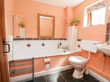 A bathroom with a bathtub toilet and sink at The Old Forge Cottage in Kilkhampton