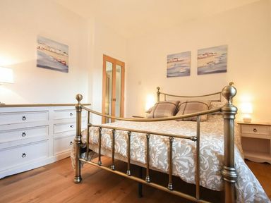 A bedroom with a metal bed frame a chest of drawers and bedside tables at The Loft (Amble) in Amble