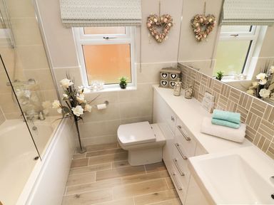 A bathroom with a bathtub shower toilet sink and countertop with decorative items at 8 Waterside Wood White Cross Bay near Troutbeck Bridge
