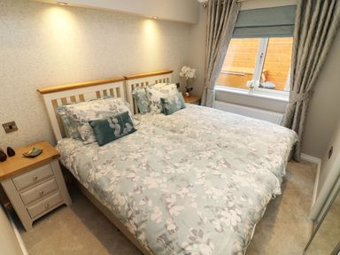A bedroom with two single beds joined together bedside tables and a window with curtains at 8 Waterside Wood White Cross Bay near Troutbeck Bridge