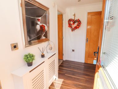 A hallway with wooden doors a white radiator cover with decorative items and a heart-shaped wall decoration at Bowness 66 in Troutbeck Bridge
