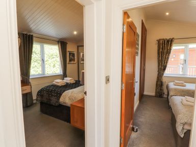 Two bedrooms each with a window beds nightstands and towels at Bowness 66 in Troutbeck Bridge