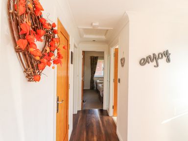 A hallway with wooden doors a wreath on one wall and the word enjoy on another wall at Bowness 66 in Troutbeck Bridge