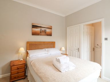 A bedroom with a bed with folded towels on it two bedside tables with lamps and two doors at Brantfell Lodge in Bowness-On-Windermere