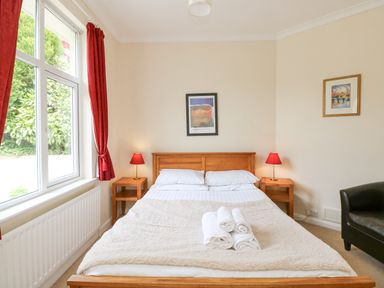 A bedroom with a wooden bed frame and white bedding with rolled towels on the bed at Brantfell Lodge in Bowness-On-Windermere