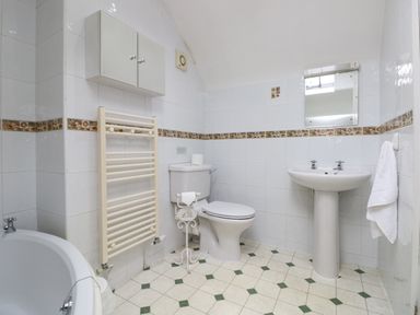 A bathroom with a toilet sink bathtub wall cabinet heated towel rail and towel at Brantfell Lodge in Bowness-On-Windermere