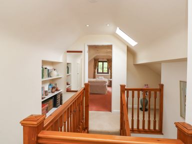 An upper floor hallway with wooden railing built in shelves and a view into a bedroom at Brantfell Lodge in Bowness-On-Windermere