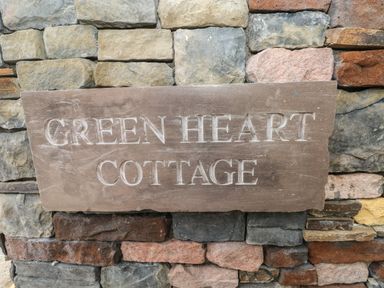 A stone plaque with the words Green Heart Cottage mounted on a multicolored stone wall at Greenheart Cottage in Pontrhydyfen