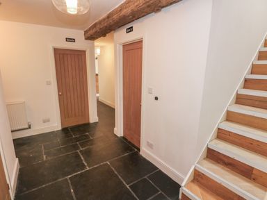 A hallway with two wooden doors labeled bedroom one and bedroom two wooden stairs and a ceiling beam at Greenheart Cottage in Pontrhydyfen