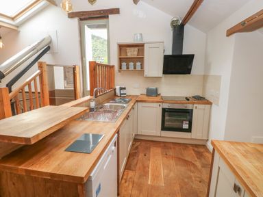 A kitchen with wooden countertops a sink an oven and stove at Greenheart Cottage in Pontrhydyfen